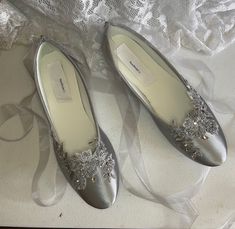 two pairs of silver shoes with flowers on them