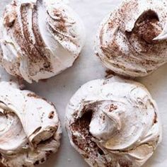 four frosted donuts sitting on top of a piece of parchment paper