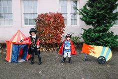 two children dressed in costumes standing next to tents