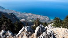 a view from the top of a mountain looking down at some mountains and water in the distance