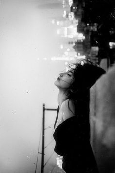 a black and white photo of a woman leaning against a wall with her eyes closed