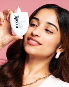 a woman holding up a bottle of lotion to her face