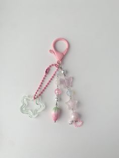 a key chain with charms attached to it on a white surface and a pink clip