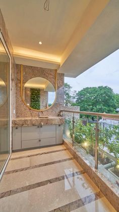 a bathroom with a large mirror and tiled flooring next to a balcony overlooking the trees