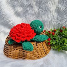 a crocheted turtle sitting on top of a basket next to a plant