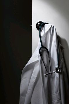 a stethoscope hanging from the side of a white coat on a wall