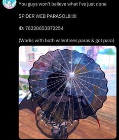 an umbrella that is on top of a wooden table in front of a window with the caption spider web parasol