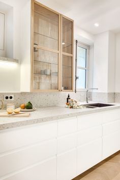 a kitchen with white cabinets and marble counter tops