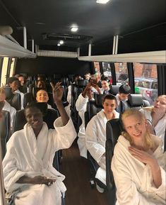 a group of people riding on the back of a bus with their hands in the air