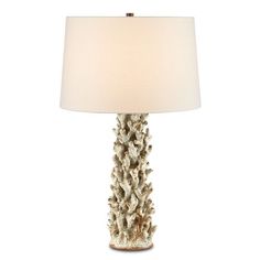 a table lamp with a white shade on it and pine cone design in the center