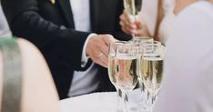 a man and woman are holding champagne flutes in their hands as they sit at a table