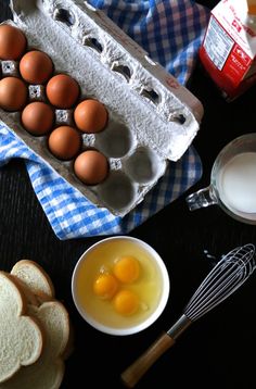 eggs, bread and butter are on the table next to an open carton of milk