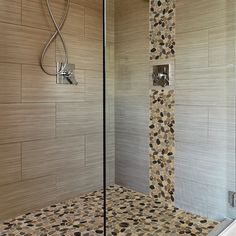 a walk in shower sitting next to a tiled wall and floor covered in pebbles on the ground