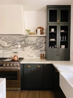 a kitchen with marble counter tops and black cabinets, along with an open shelving unit