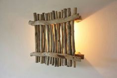 a wall light made out of driftwood sticks on the side of a white wall