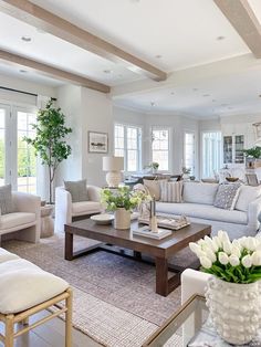 a living room filled with lots of furniture and flowers on top of a coffee table