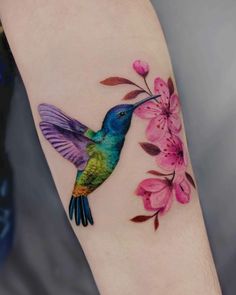 a colorful hummingbird with pink flowers on its arm