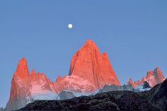 the moon is setting behind some mountains