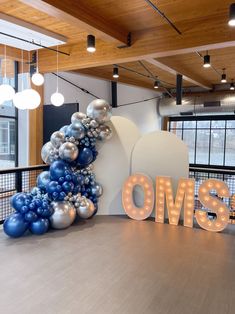 the letters oms are lit up in front of an illuminated sign and balloon arch