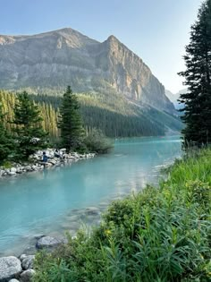 there is a man fishing on the river in the mountains with blue water and green trees