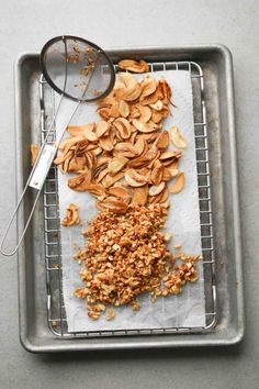 a metal tray topped with sliced almonds next to a magnifying glass and spoon