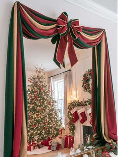 a decorated christmas tree in front of a mirror with red and green ribbon on it