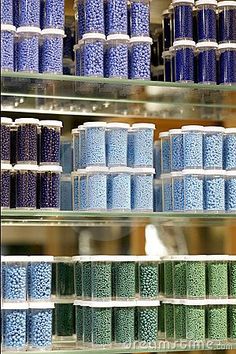 several shelves filled with blue and green candies in plastic containers next to each other