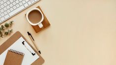 an office desk with a keyboard, mouse and coffee cup on it next to a notepad