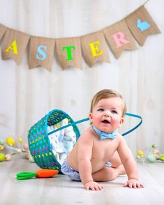 a baby is sitting on the floor in front of a banner with easter eggs and carrots