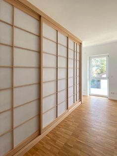 an empty room with wooden flooring and sliding glass doors on the wall to let in light