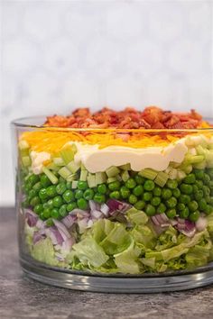 a salad in a glass bowl with bacon and lettuce on the side, ready to be eaten