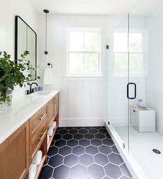 a bathroom with black and white tile flooring next to a large mirror on the wall