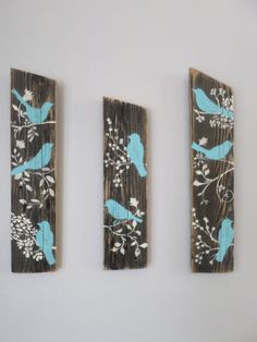 three pieces of wood with birds painted on them, one is blue and the other has white flowers