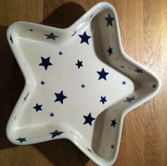 a white and blue star shaped dish sitting on top of a wooden table next to a wall