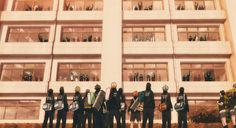 a group of people standing in front of a tall building with windows on each side