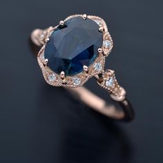 an oval shaped blue sapphire and diamond ring on a black surface with white diamonds around it