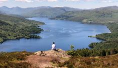 a person sitting on top of a hill overlooking a lake