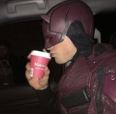 a man dressed as batman drinking out of a cup