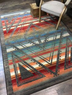 a colorful area rug with an abstract design on the bottom and sides, in front of a chair