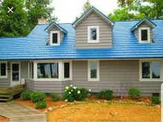 a gray house with blue roof and white windows