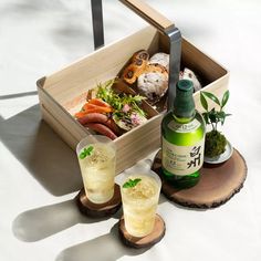 an assortment of food and drinks sitting in a wooden box on top of a table