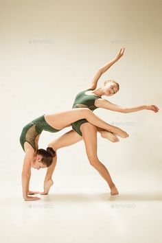 two young women in leotards are doing acrobatic moves - stock photo - images