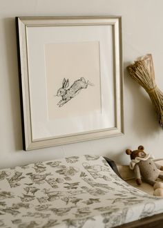 a frame hanging on the wall above a bed with a stuffed animal next to it