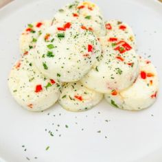 some food is on a white plate with green sprinkles and red peppers