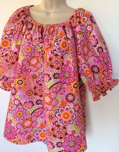 This handmade blouse is made in a 1960's style with puffy sleeves and elastic neckline. The fabric is a polyester/cotton seersucker with the wrinkling or puckering in it. It is sized 12-14 misses. The neckline and short sleeves are gathered with elastic. The print is bright floral great for spring and summer. This blouse can easily be worn by teen to adult. Summer Floral Print Peasant Top With Balloon Sleeves, Spring Multicolor Cotton Peasant Top, Spring Retro Blouse With Puff Sleeves, Retro Puff Sleeve Blouse For Spring, Multicolor Fitted Blouse With Balloon Sleeves, Fitted Multicolor Blouse With Balloon Sleeves, Fitted Multicolor Balloon Sleeve Blouse, Retro Cotton Blouse With Puff Sleeves, Pink Cotton Smock Blouse