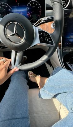 a woman is sitting in the driver's seat of a mercedes vehicle with her hands on the steering wheel