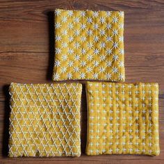 three pieces of yellow fabric sitting on top of a wooden table