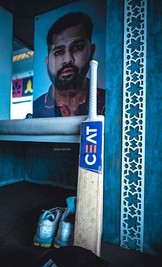 a baseball bat sitting on top of a floor next to a blue wall with a man's face in the background