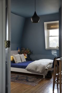 a bedroom with blue walls and wooden floors