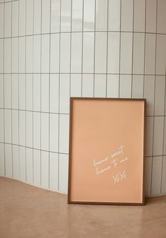 a white tile wall with a pink frame and writing on it